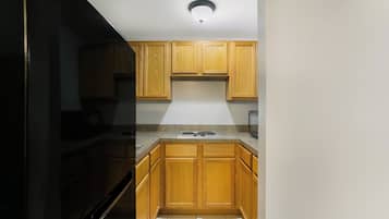 A kitchen with wooden cabinets, a stainless steel refrigerator, and a built-in microwave.