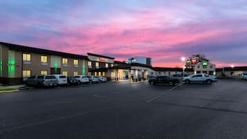 Un parking rempli de voitures, un bâtiment avec une enseigne « Red Roof », et un ciel au coucher du soleil.