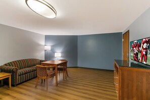 Uma sala de estar moderna com um sofá, uma mesa de jantar, cadeiras, uma televisão e um abajur.