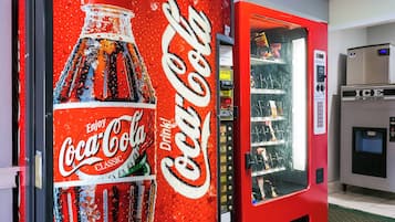 Un distributeur automatique de Coca-Cola doté d’une grande affiche publicitaire, d’un compartiment pour les pièces et d’un système de distribution de boissons.