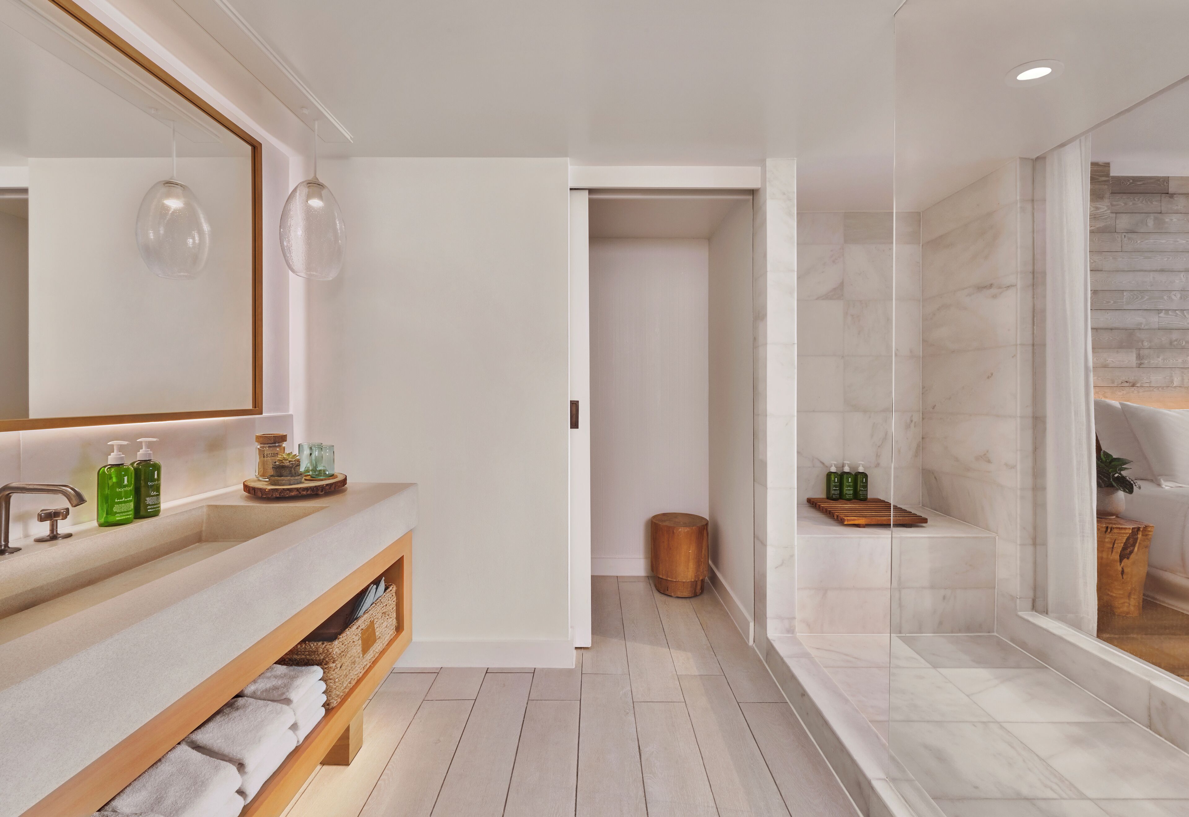 A modern bathroom with a large mirror, wooden vanity, and a shower area.