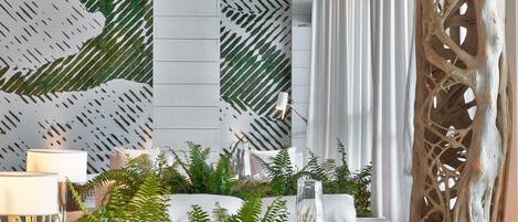 A modern interior with a white sofa, decorative wall panels, and natural elements like plants and a wooden sculpture.