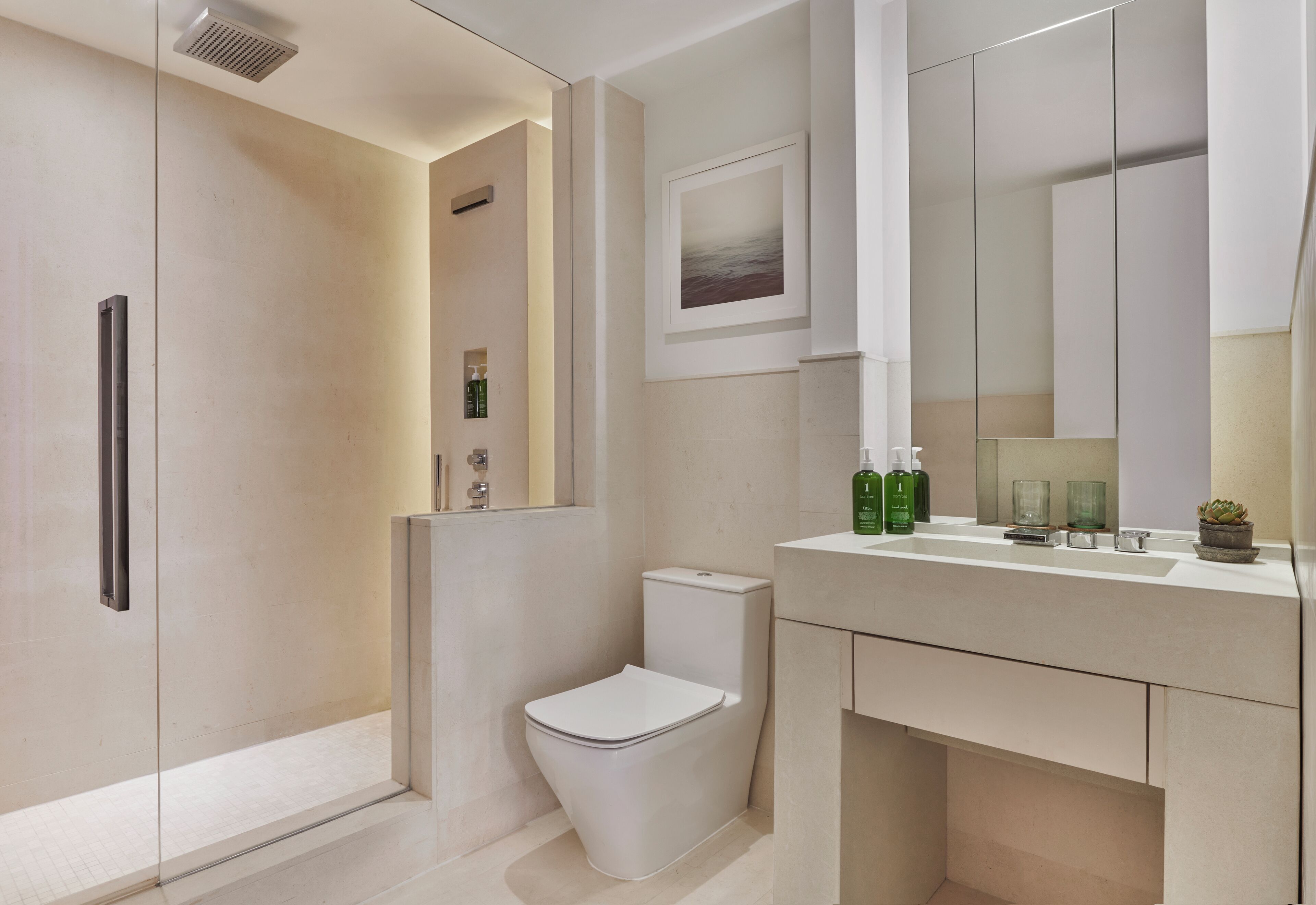 Un baño moderno con cabina de ducha de vidrio, inodoro y tocador con espejo.