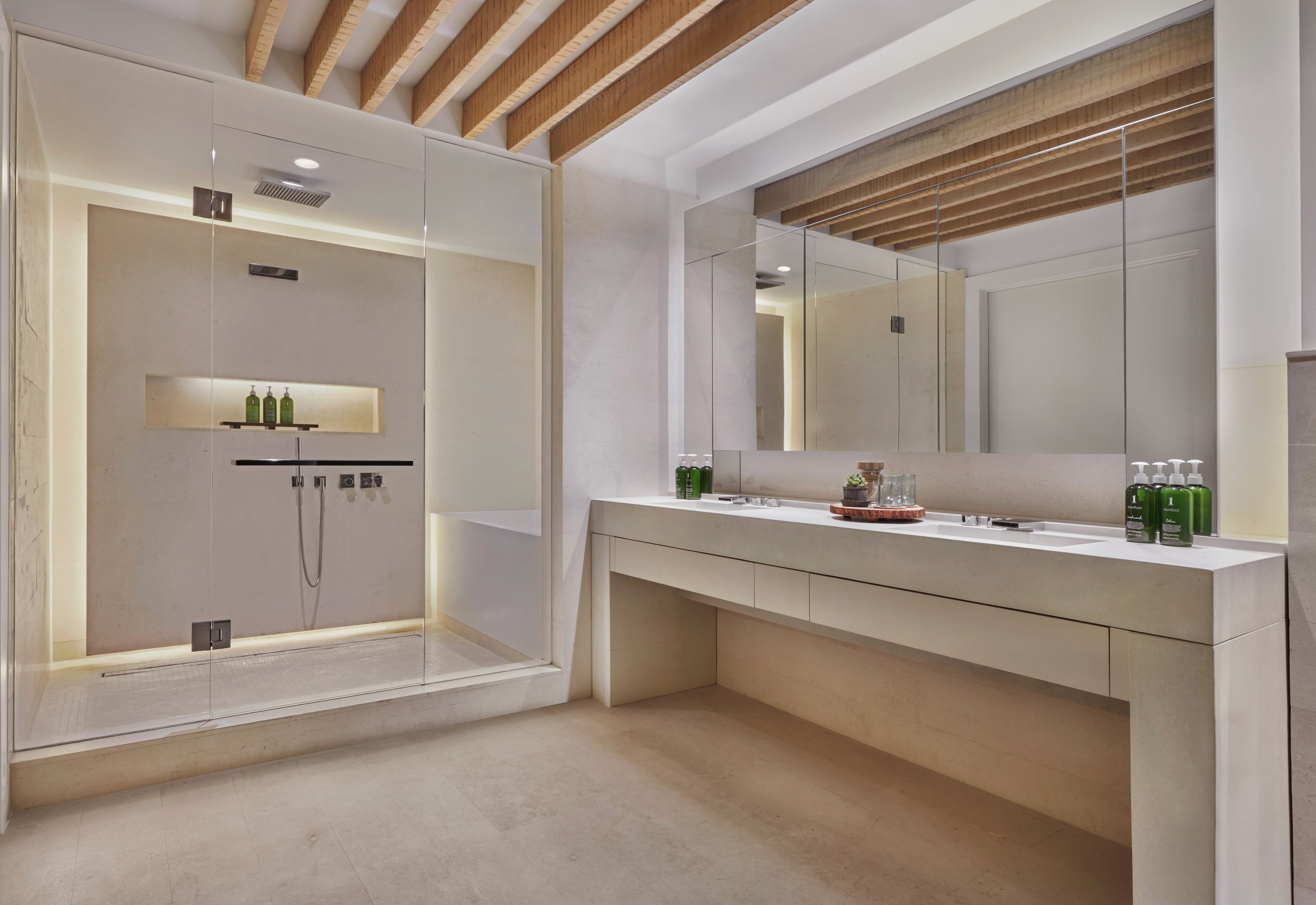 Un baño moderno con ducha envuelta en vidrio, un espejo grande y un tocador con encimera.