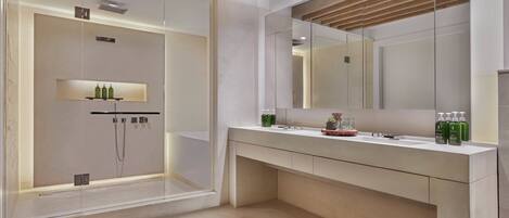 Un baño moderno con ducha envuelta en vidrio, un espejo grande y un tocador con encimera.