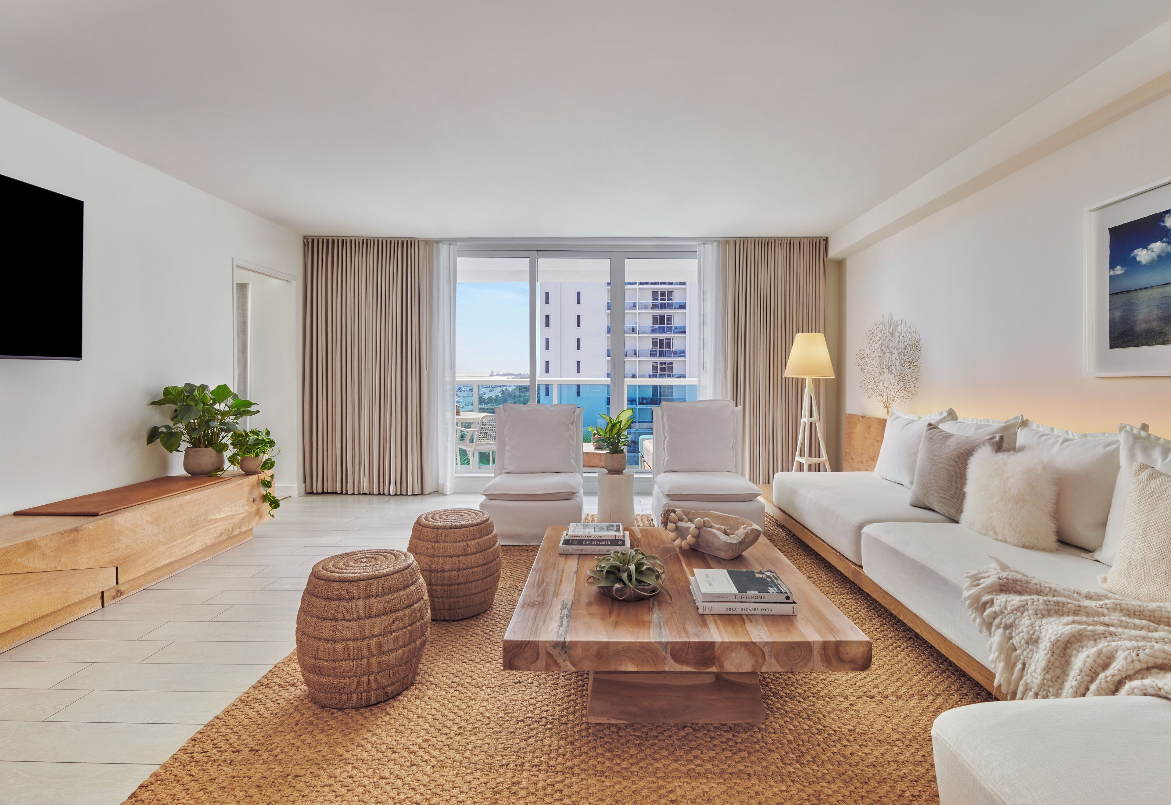 A modern living room with a large window, a sofa, a coffee table, and a TV.