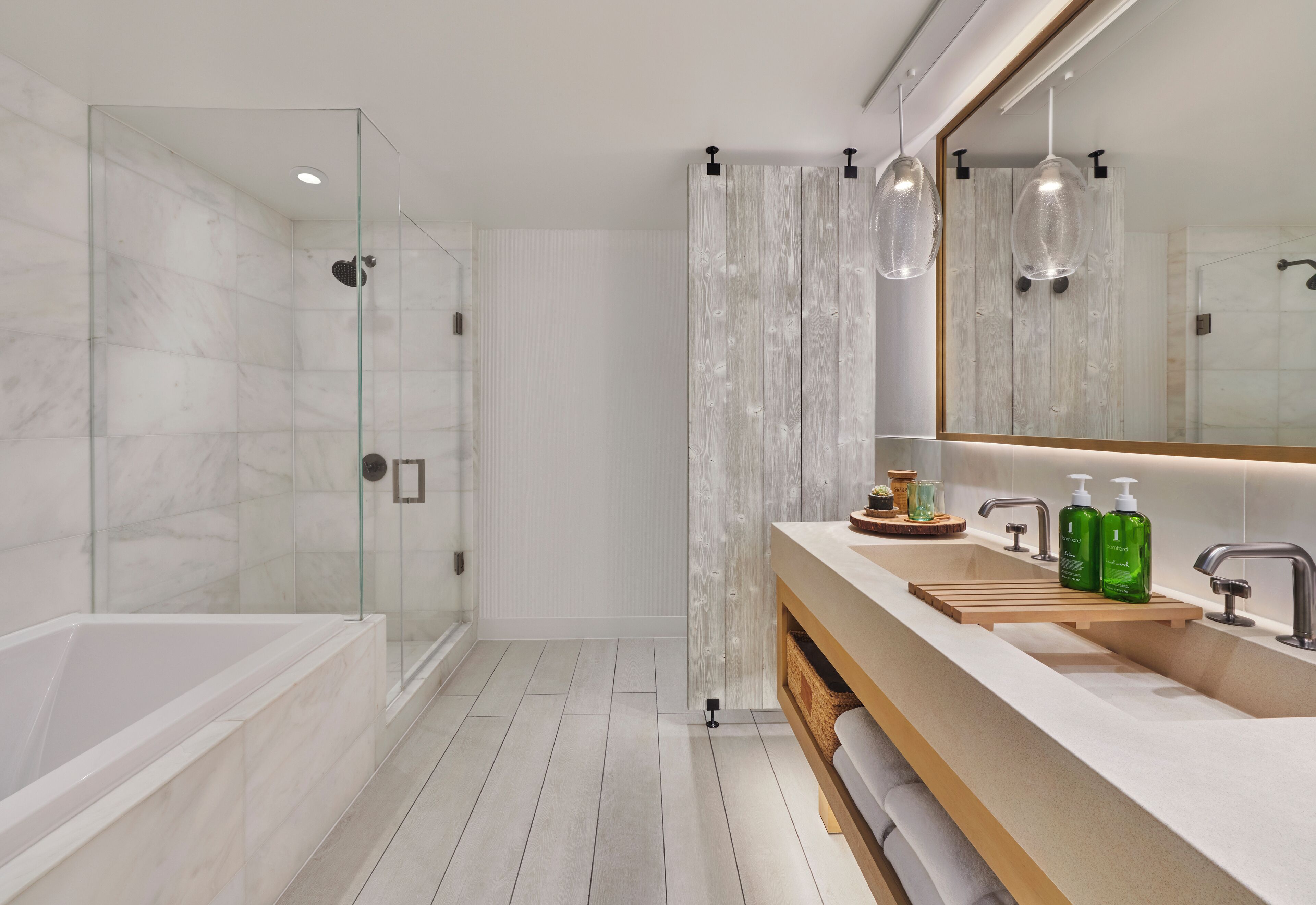 A modern bathroom with a glass-enclosed shower, a vanity with a wooden shelf, and a large mirror.