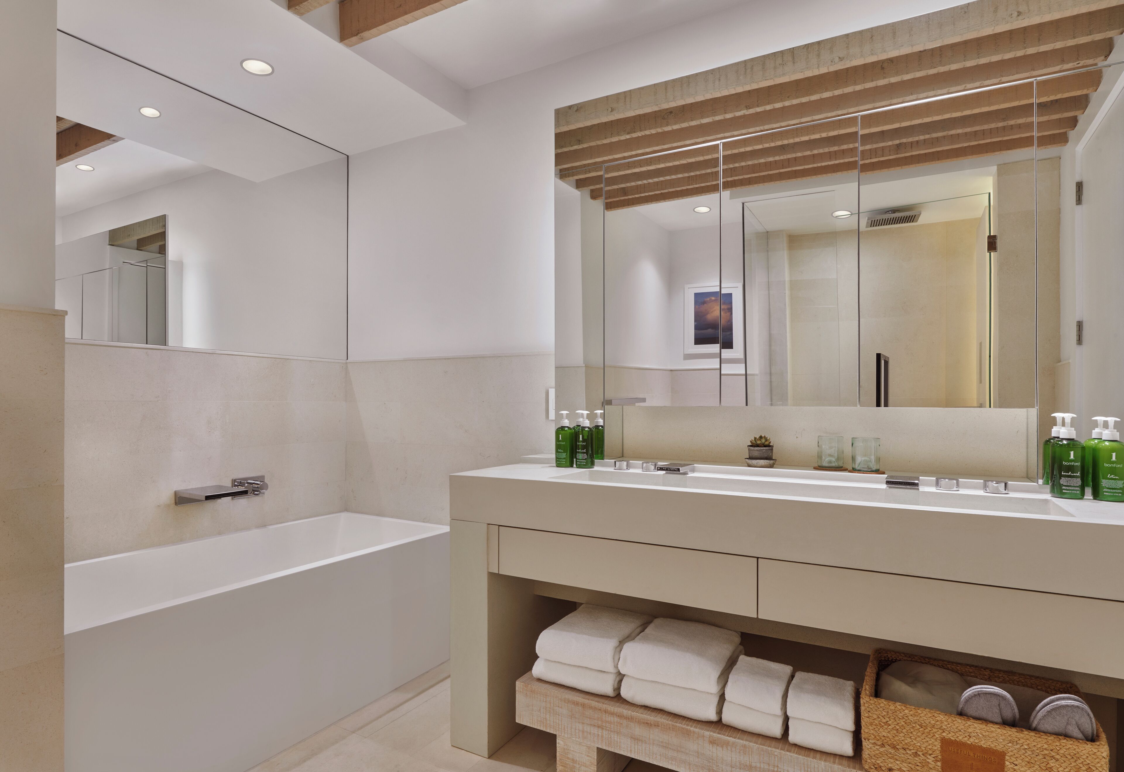 A modern bathroom with a freestanding bathtub, a large mirror, and a vanity with toiletries.