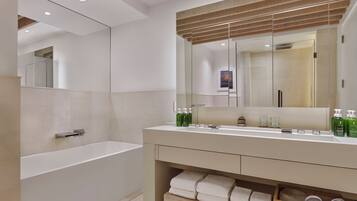 A modern bathroom with a freestanding bathtub, a large mirror, and a vanity with toiletries.