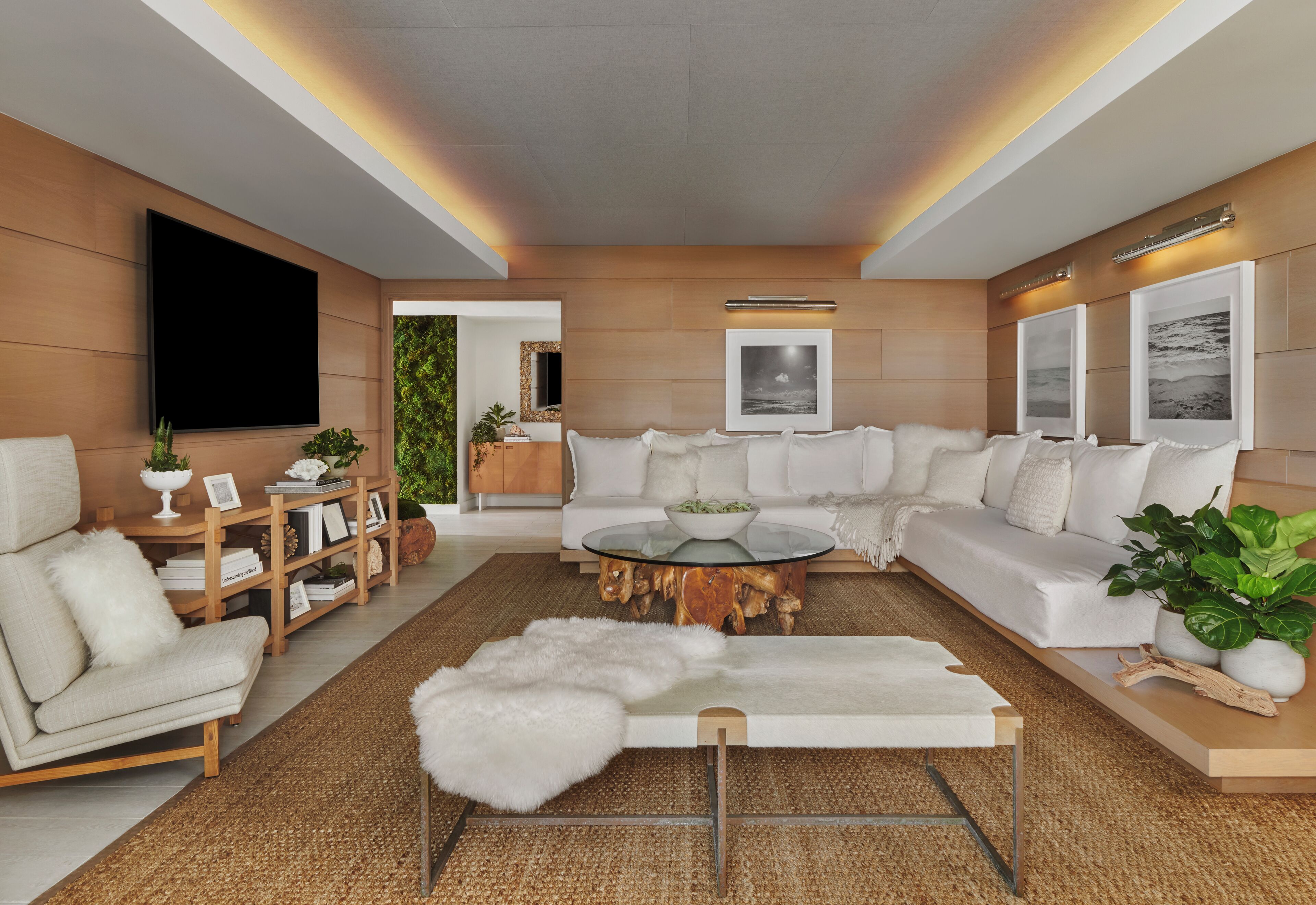 Una sala de estar moderna con un sofá modular, una mesa de centro de vidrio y un televisor de pantalla plana montado en la pared.