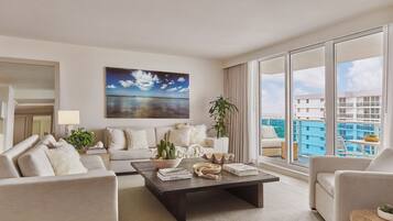 A modern living room with a large window, a painting of a beach, and a view of a cityscape.