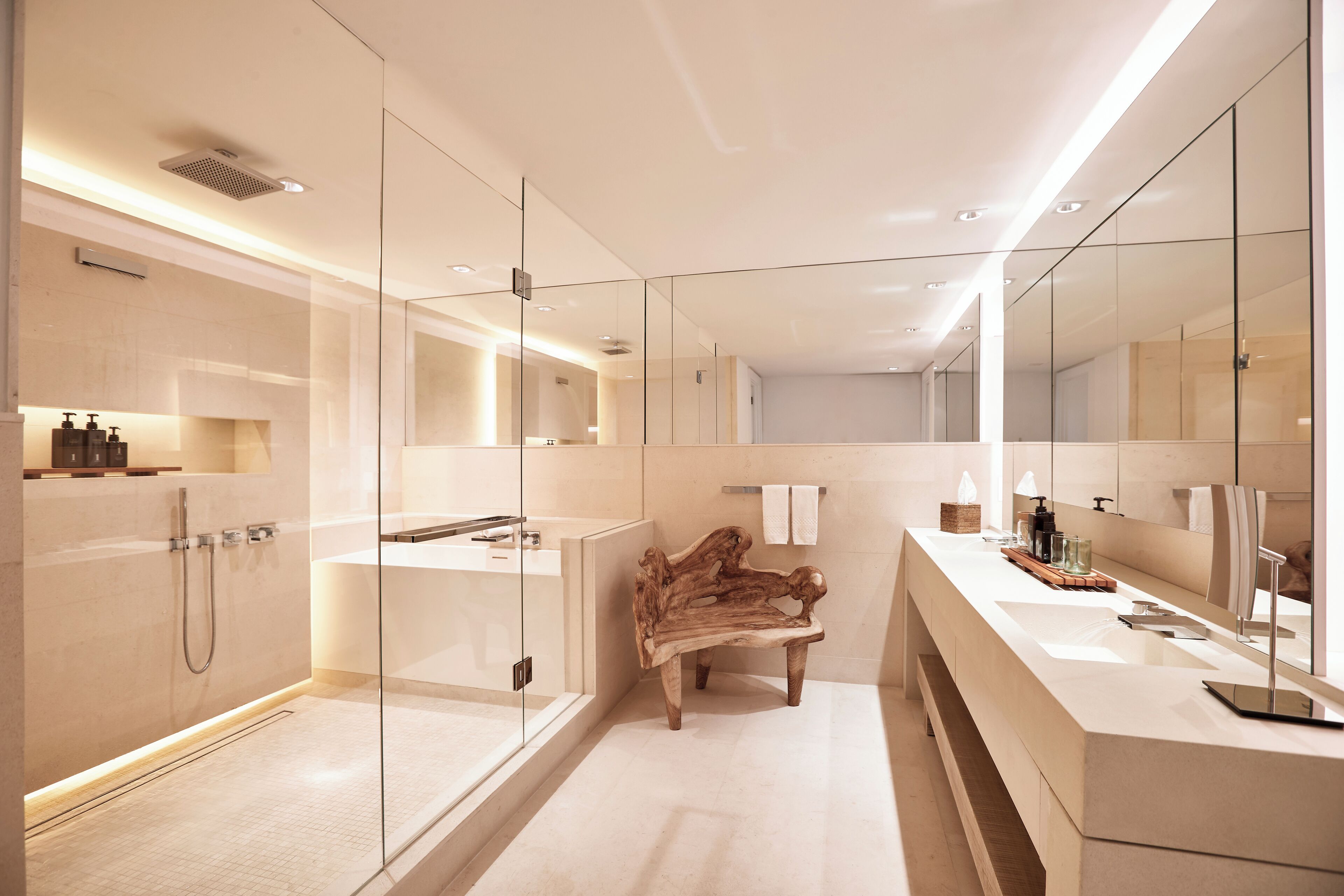 A modern bathroom with a glass-enclosed shower, a wooden bench, and a large mirror.