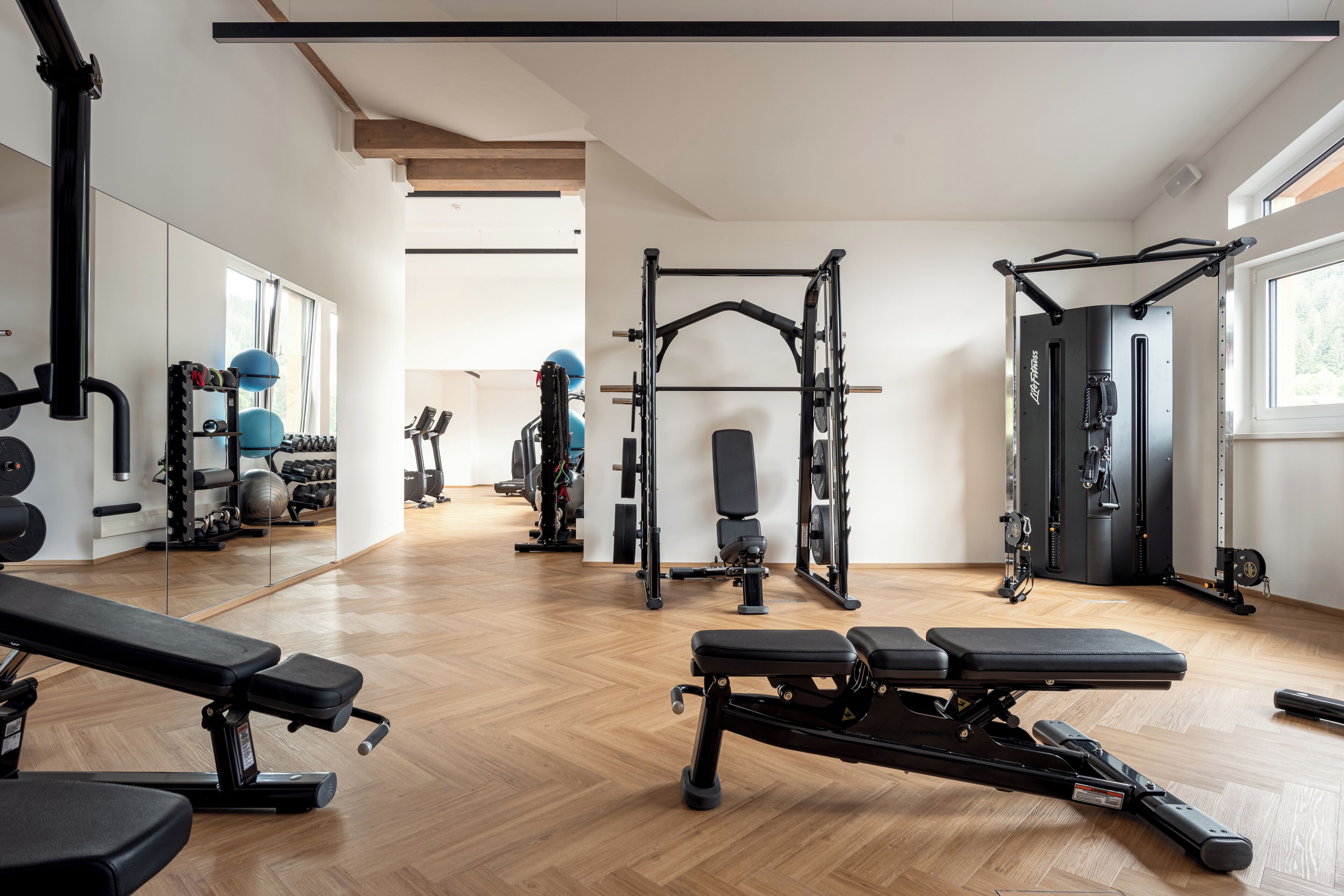 Una palestra con attrezzature per esercizi, panche e uno specchio lungo la parete.