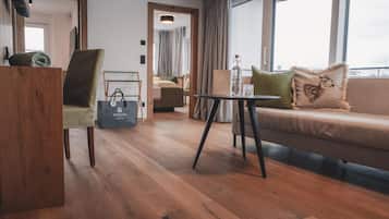 Una sala de estar moderna con piso de madera, un sofá con cojines decorativos, una mesita y una silla.