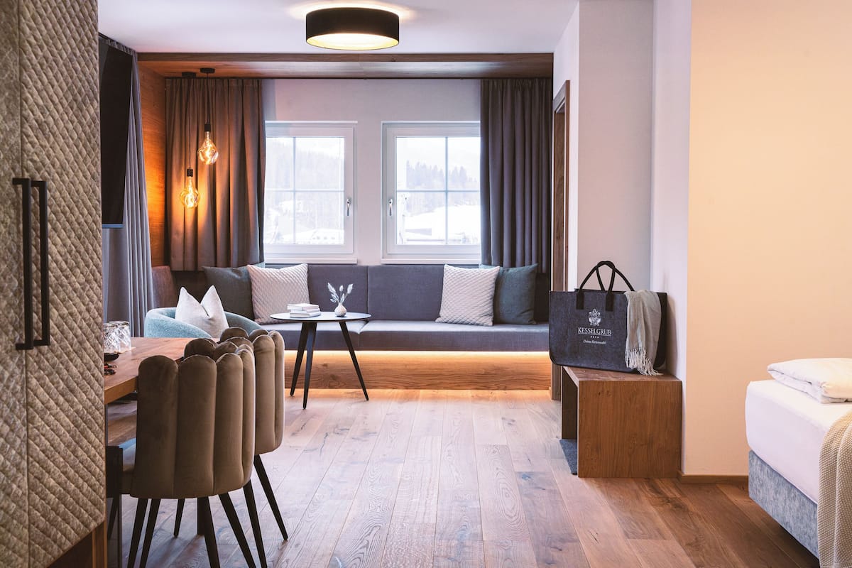 A modern room with a wooden floor, a sofa with cushions, a small table, and a bench with a bag.