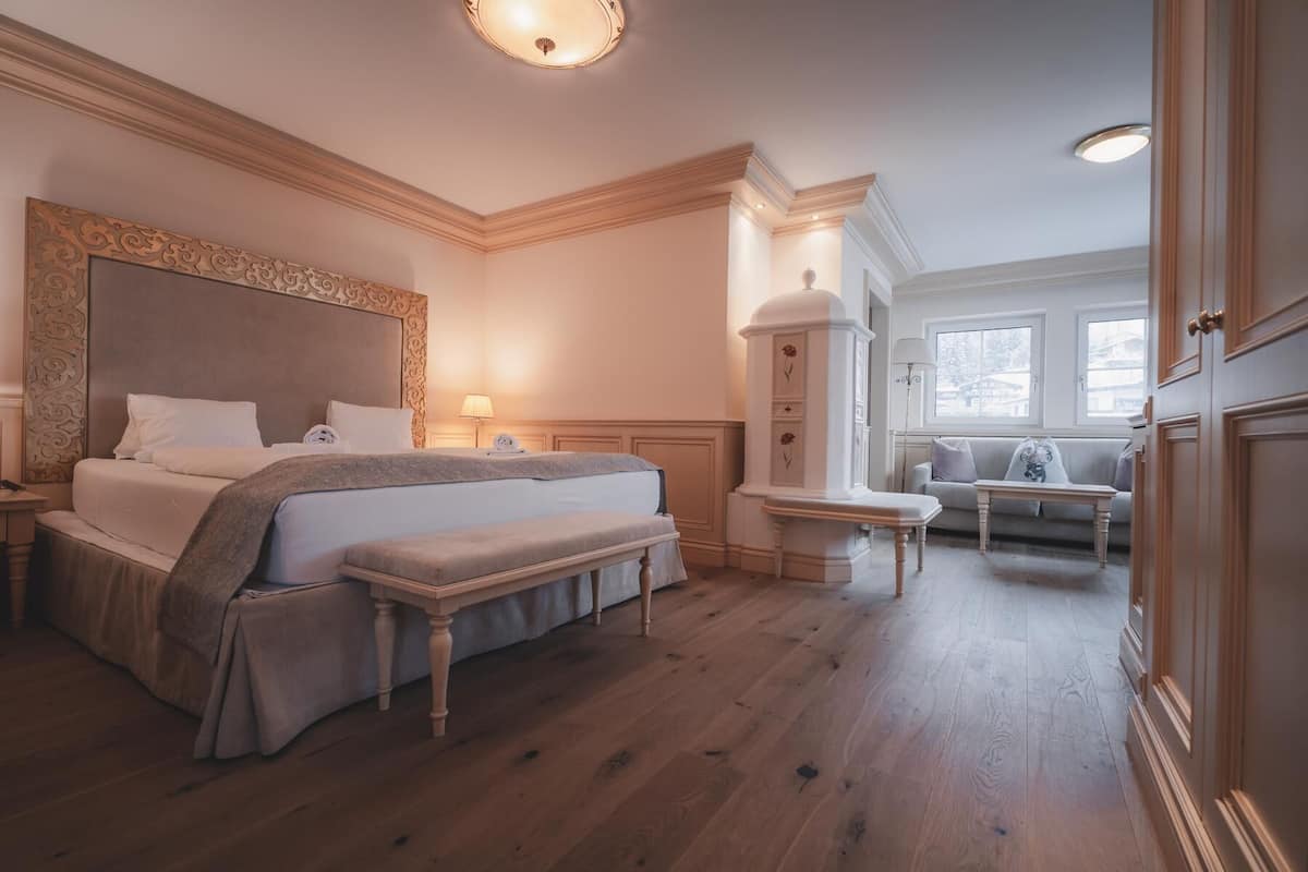 A bedroom with a large bed, bedside tables, a bench, a sofa, and a small table.