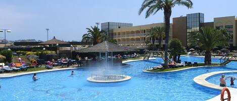 Een binnenzwembad, 6 buitenzwembaden en parasols bij het zwembad