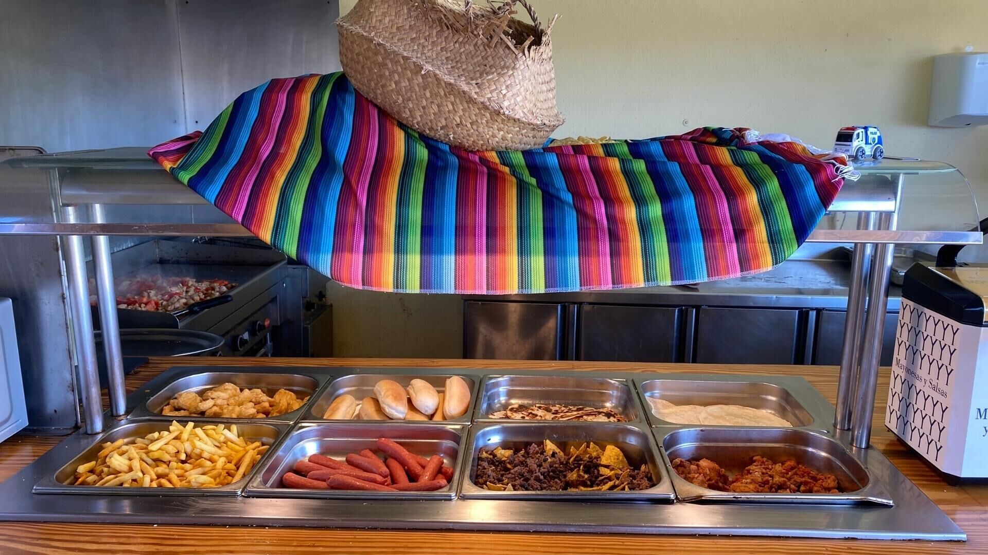 Un buffet proposant une variété de plats, notamment des frites, des hot-dogs et des nachos.