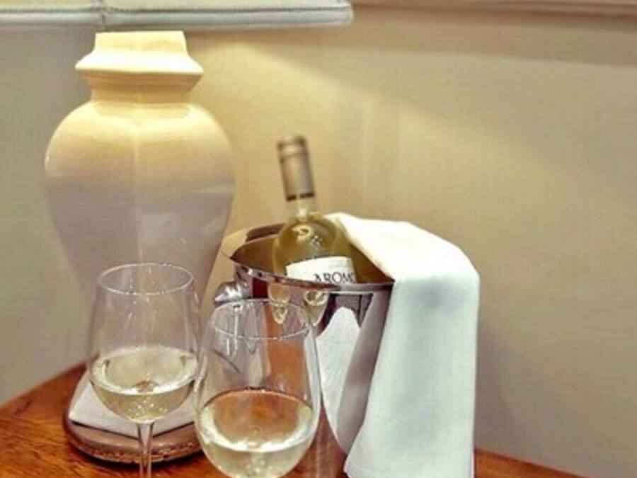 Een tafel met twee glazen witte wijn, een wijnfles, een lamp en een menukaart.