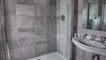 A modern bathroom with a glass-enclosed shower, a white sink, and marble tiles.