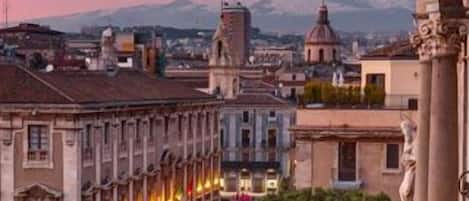 A historic building with classical architecture, a central courtyard, and a view of a mountain in the background.