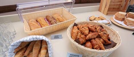 A buffet with labeled baskets of bread and croissants.