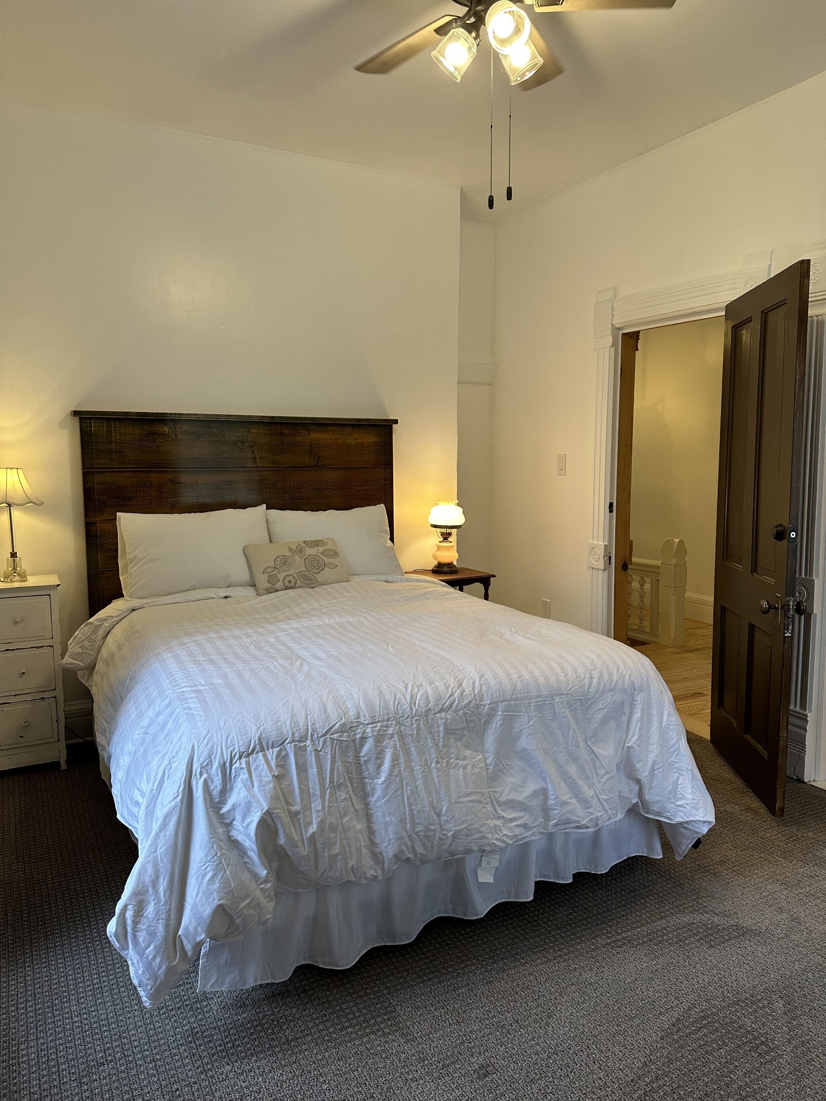 Een keurig opgemaakt bed met een houten hoofdeinde, een bedlampje en een nachtkastje.