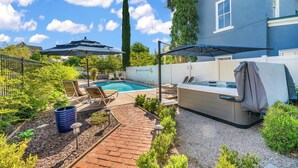 A backyard with a swimming pool, lounge chairs, a hot tub, and a pergola. - The Cottage @ 241 North (St. George)