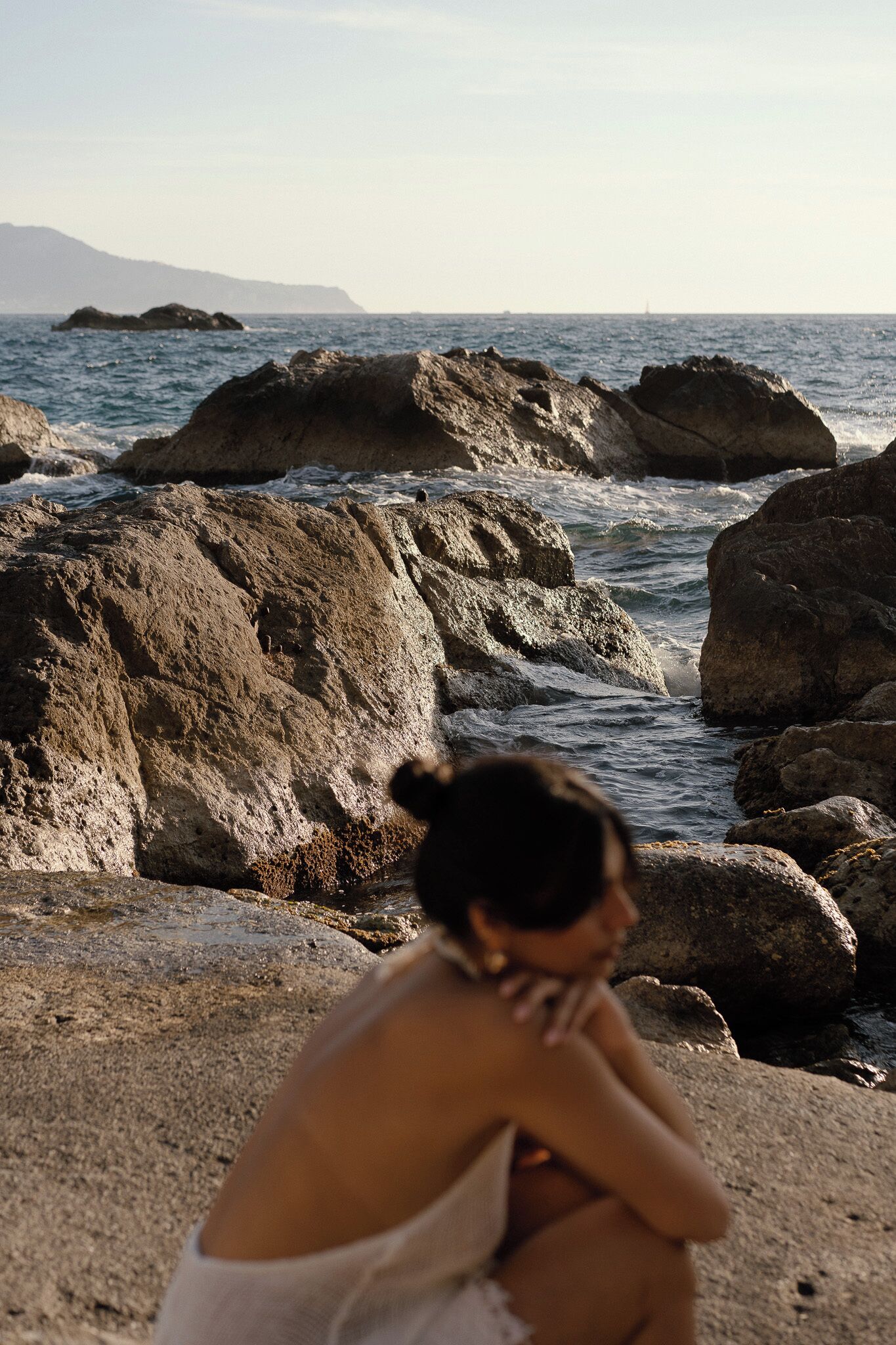 A rocky beach with waves crashing against large boulders.