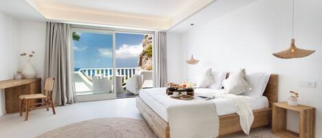 Une chambre moderne avec un grand lit, un bureau et une vue sur l’océan.
