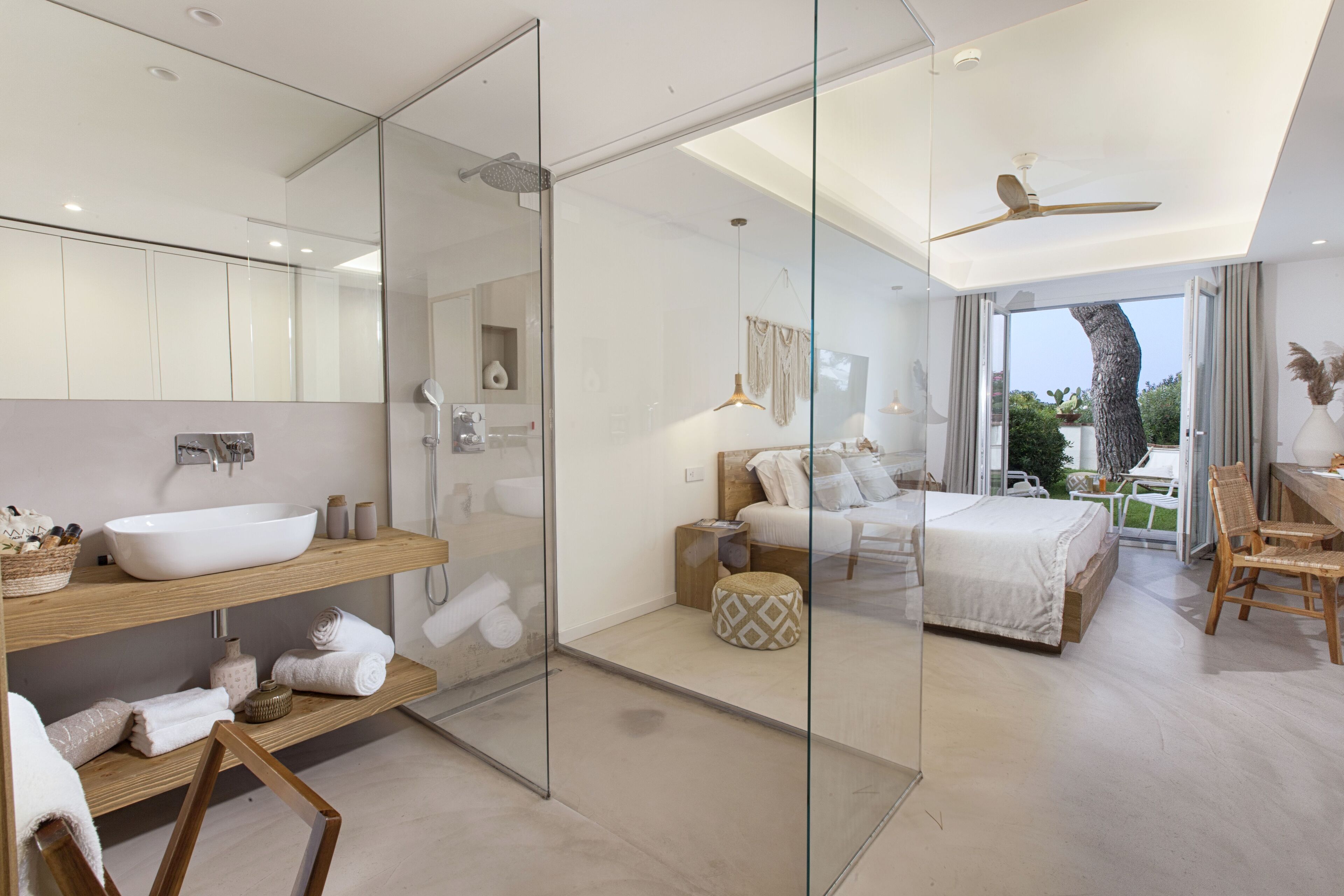 Ein modernes Schlafzimmer mit einem großen Bett, einer Dusche mit Glastrennwand und einem Balkon mit Blick.