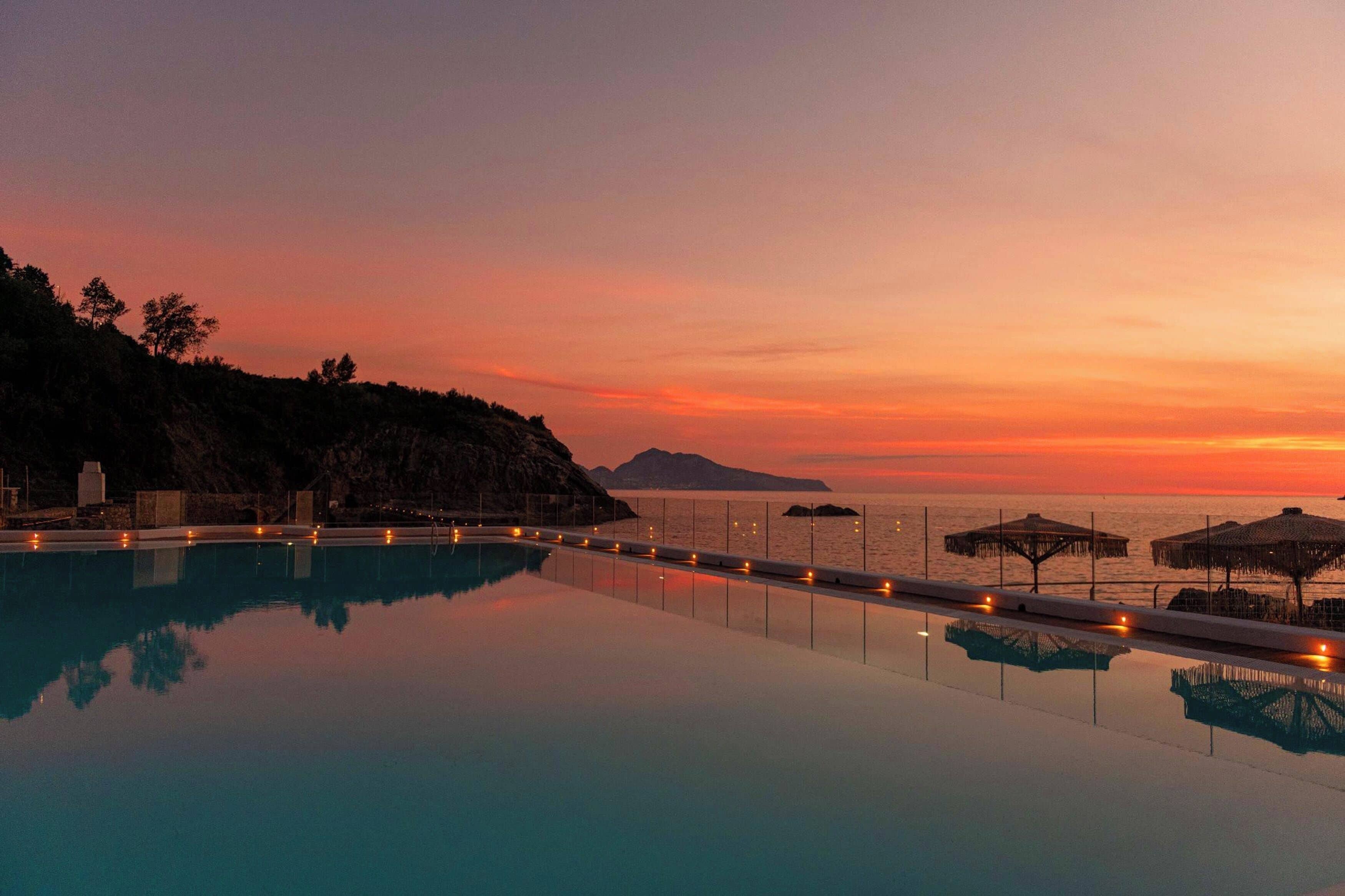 Una piscina infinita tranquila al atardecer, con vistas al océano y a islas distantes.