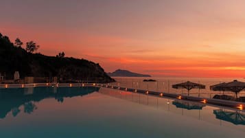 Una piscina infinita tranquila al atardecer, con vistas al océano y a islas distantes.