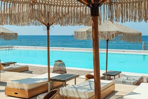 A poolside area with lounge chairs and umbrellas, overlooking a clear blue sea. - Maya Beach Resort (Massa Lubrense)