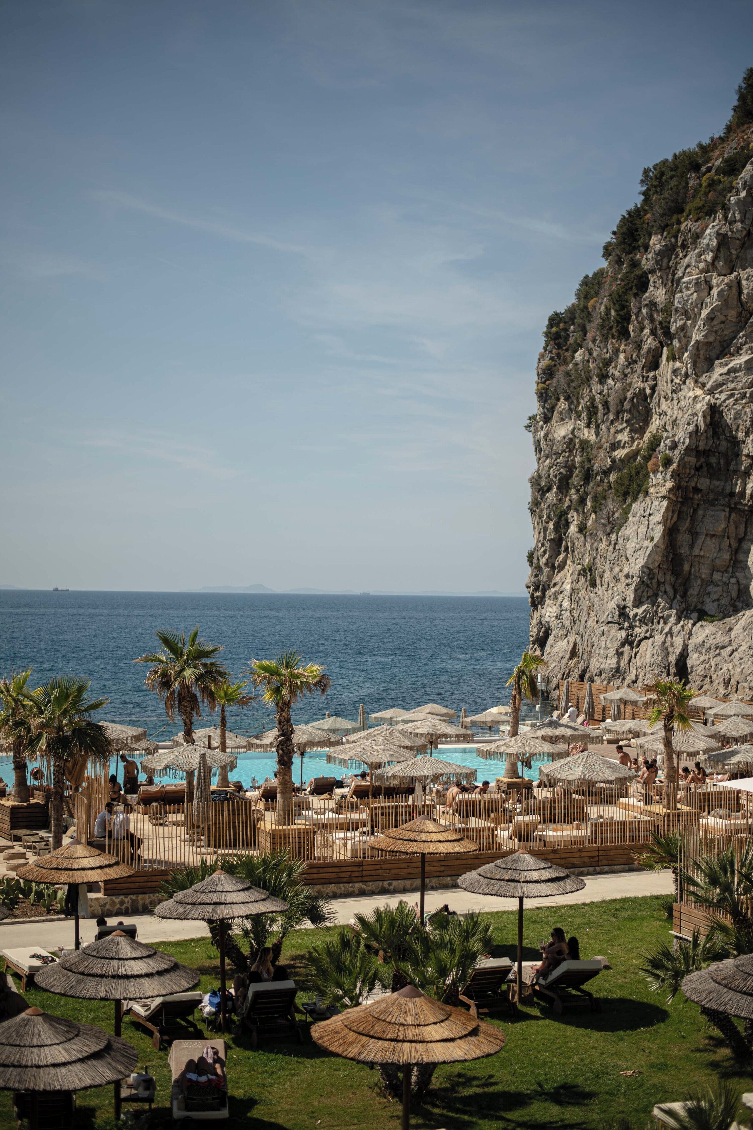 Un resort con piscina, palmeras y vista al mar.