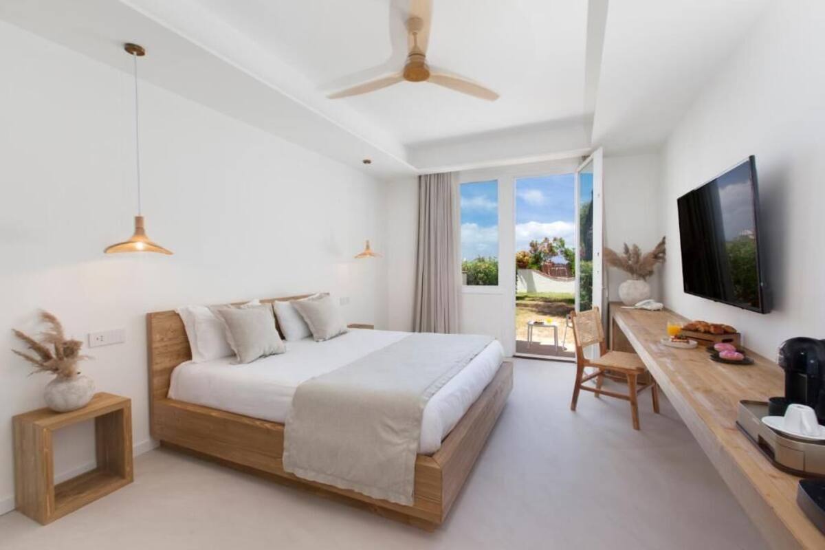Une chambre à coucher avec un lit, un bureau, une télévision et un ventilateur de plafond.