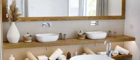 Ein modernes Badezimmer mit zwei Waschbecken, einem großen Spiegel, Holzregalen und einer Badewanne.
