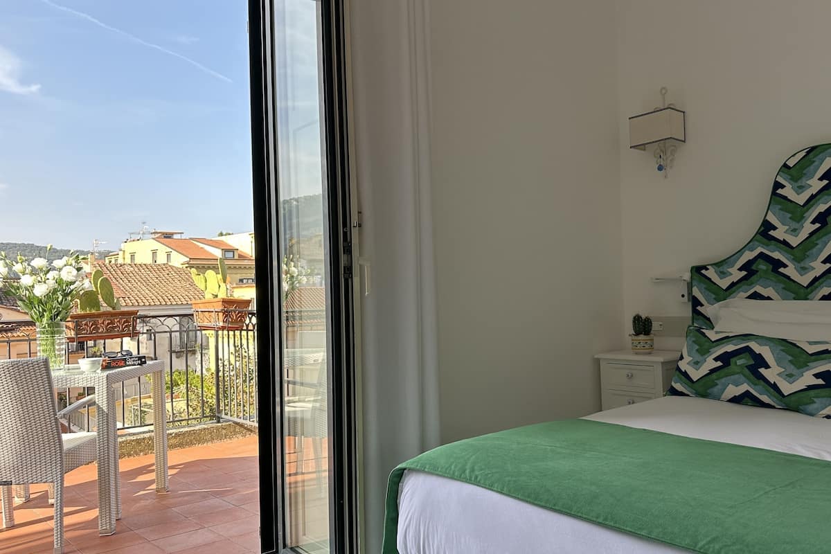 Un dormitorio con una cama grande, una mesita de noche, una ventana y vistas al exterior.