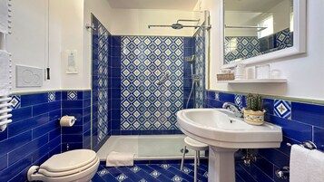 A bathroom with a shower, toilet, and sink, featuring blue and white patterned tiles.