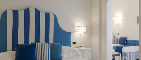 A hotel room with a large bed, a nightstand, and a mirror.