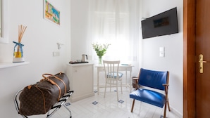 A room with a bed, a desk, a chair, a TV, and a window with curtains. - Villa di Sorrento (Sorrento)