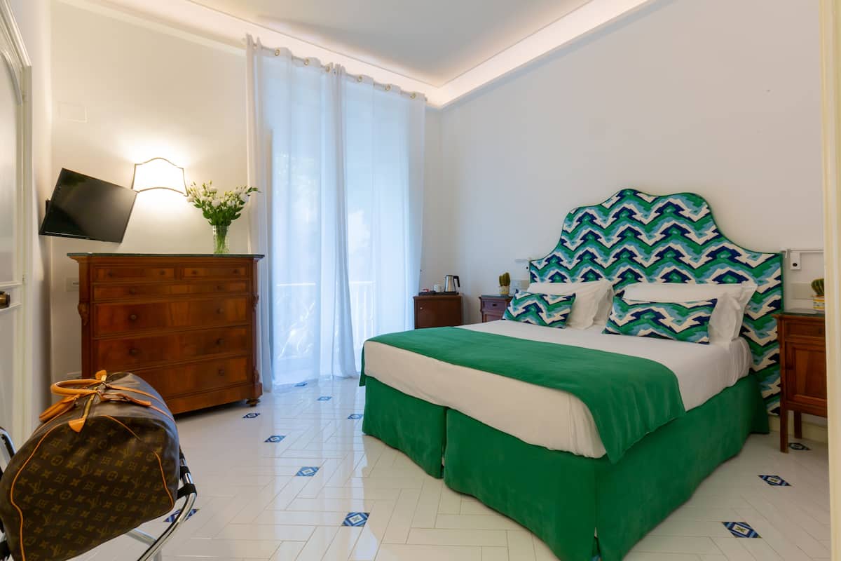 Una habitación de hotel con cama, cómoda, televisor y maleta.