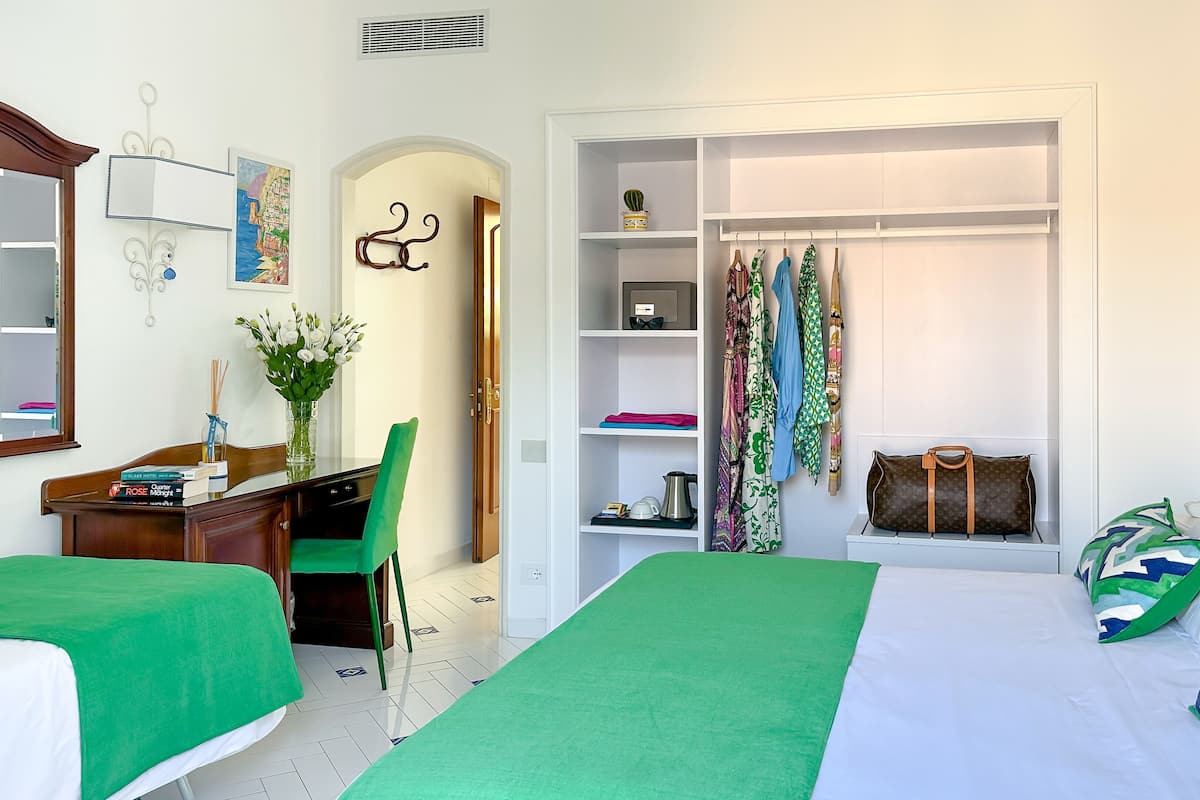 Una habitación de hotel ordenada con cama, escritorio, silla, armario y una pequeña mesa.