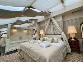 A luxurious bedroom with a large bed, canopy, and a mirror.