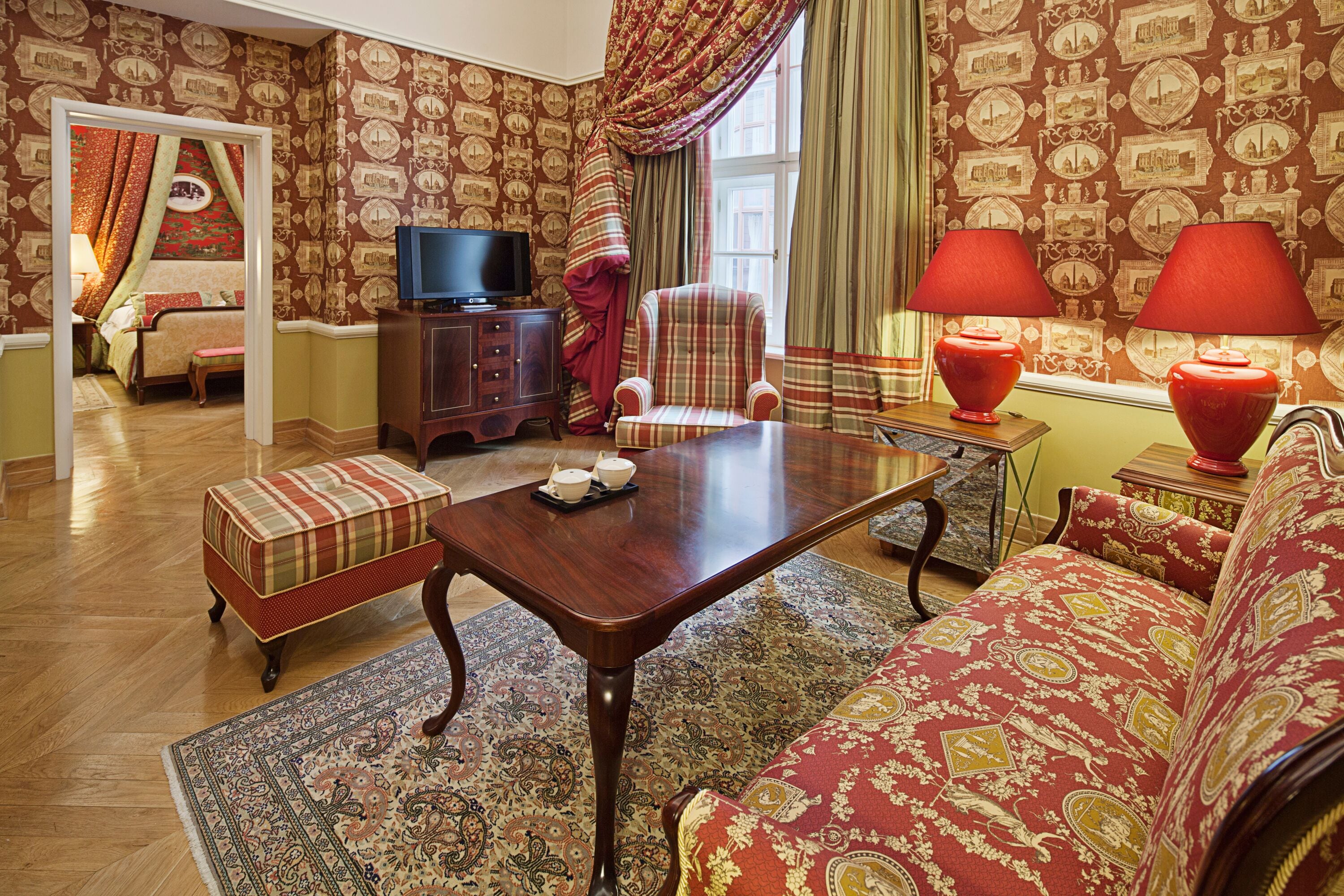 A traditional room with a wooden coffee table, a sofa, a patterned rug, and a television.