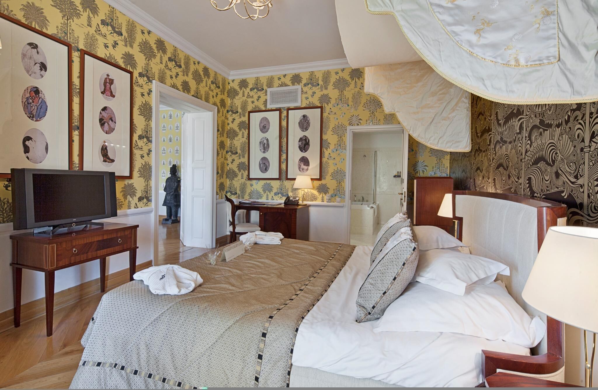 Una habitación de hotel con cama, mesitas de noche, televisión y obras de arte en las paredes.