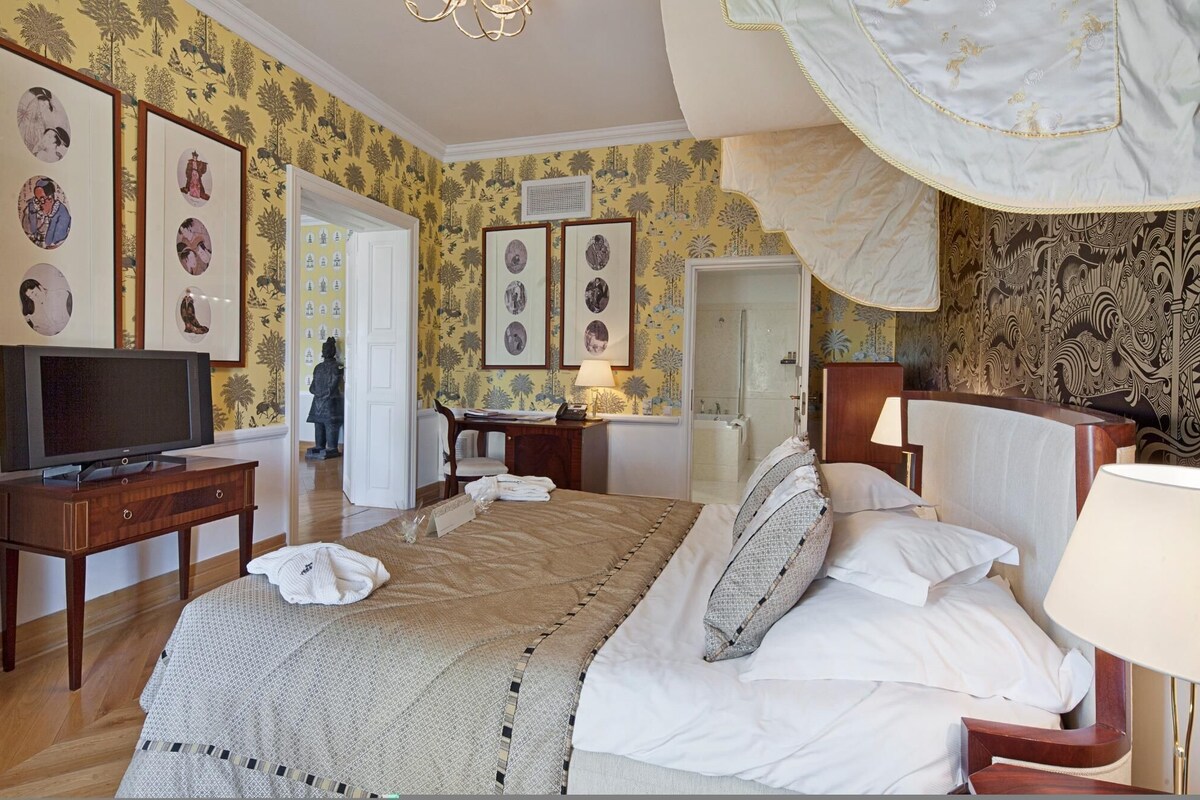 Una habitación de hotel con cama, mesitas de noche, televisión y obras de arte en las paredes.