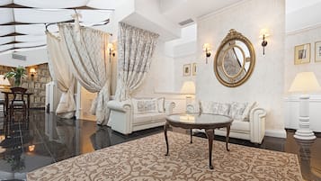 Un salon spacieux avec un canapé blanc, une table basse en verre et un tapis à motifs.