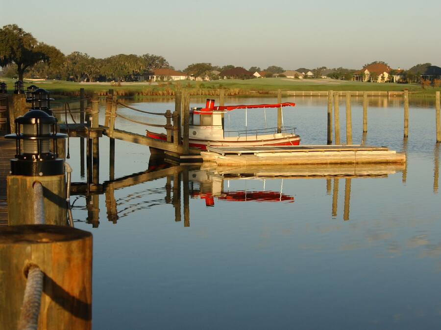 A calm lake with a dock and a boat.