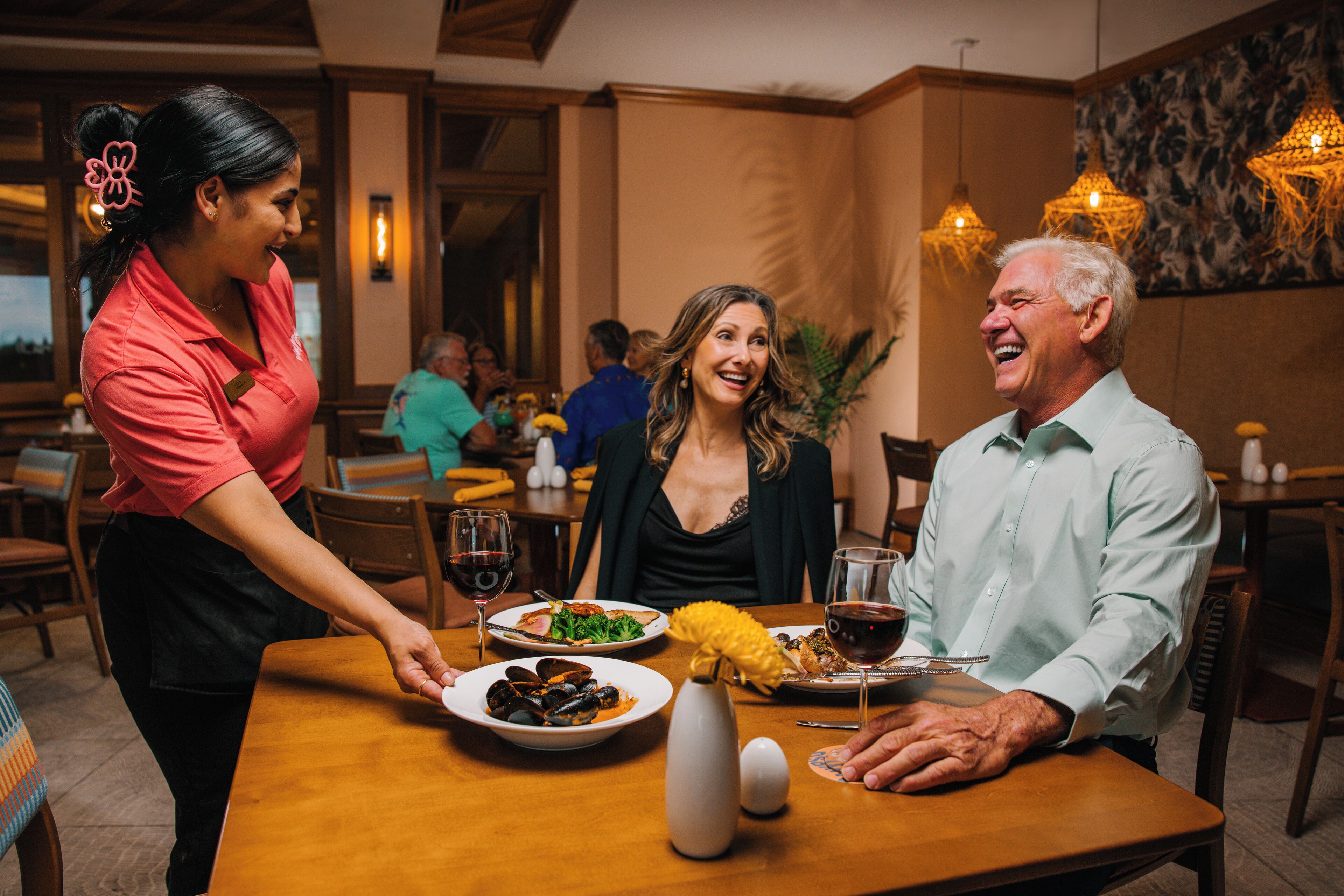 A restaurant setting with a waiter serving food to a seated couple.